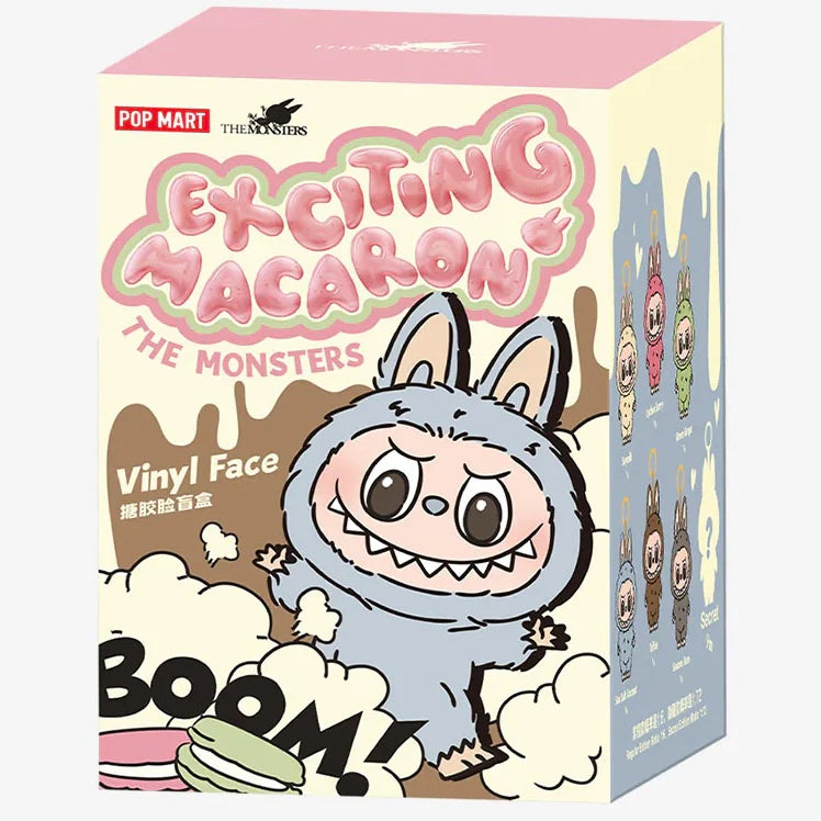 Box design of "Exciting Macaron: The Monsters" by Pop Mart. Features a cute monster in a fuzzy suit with big eyes, surrounded by colorful macarons and cartoon text "BOOM!" The tone is playful and whimsical.