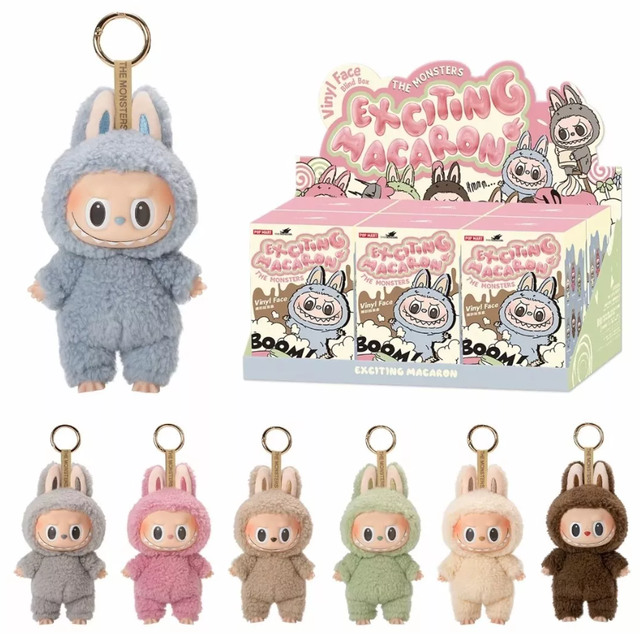 Cute plush keychains displayed with packaging. Each keychain features a wide-eyed character in colorful animal suits. Packaging says "Exciting Macaron." Vibrant, playful tone.
